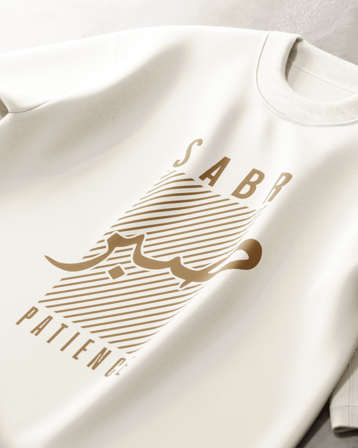White sweatshirt with gold graphic and 'Sabr Patience' text on a light gray background