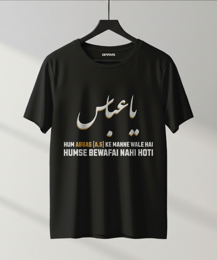 Black Islamic T-shirt with Urdu text "Ya Abbas" and white-yellow bold lettering that says "Hum Abbas (A.S) ke manne wale hai, humse bewafai nahi hoti" on a hanger.
