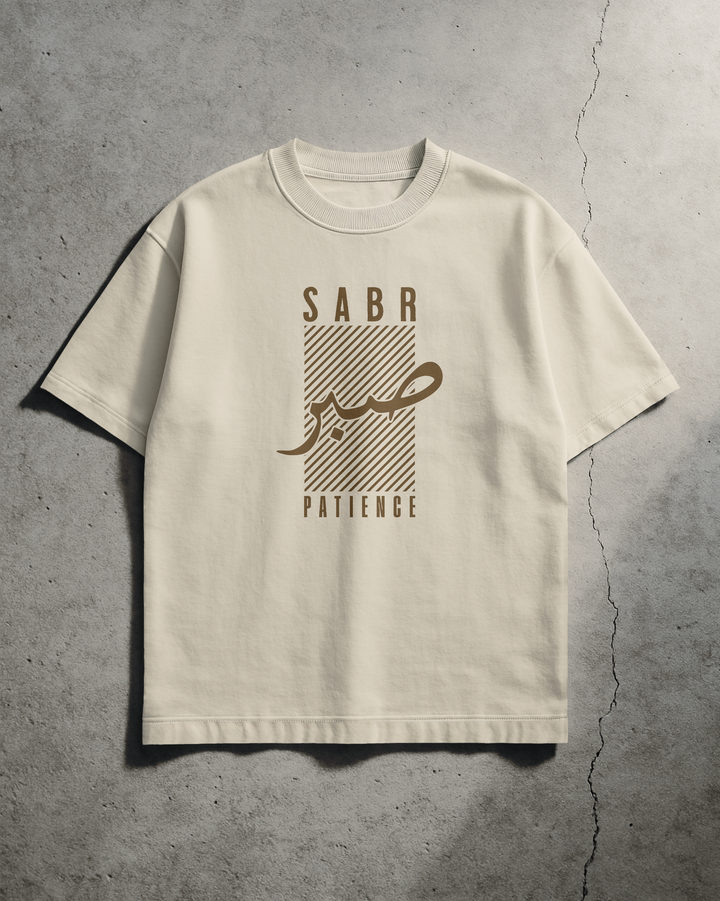 Beige t-shirt with 'SABA' and 'PATIENCE' text on a concrete surface