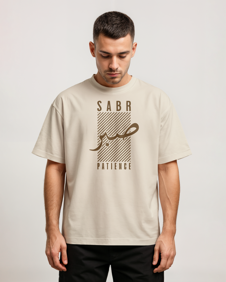 Man wearing a beige t-shirt with 'Sabr' and 'Patience' text on a plain background