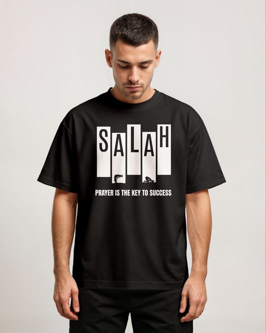 Man wearing a black t-shirt with 'SALAH' and 'PRAYER IS THE KEY TO SUCCESS' text on a plain background